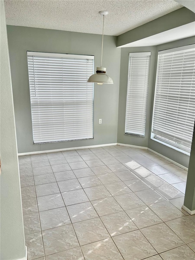 4713 Tiburon Dr, New Port Richey, FL 34655 - unfurnished dining area with a textured ceiling, baseboards, tile patterned floors, and plenty of natural light