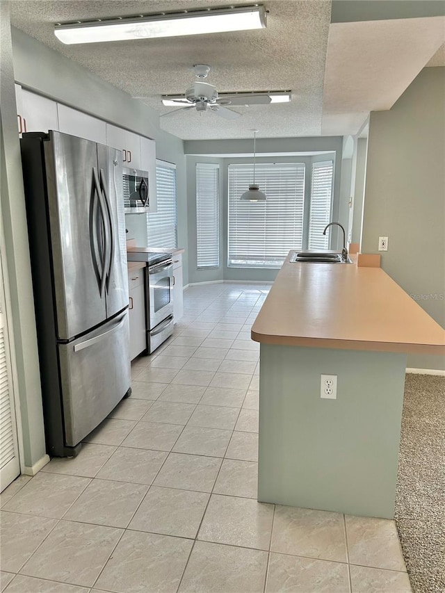 4713 Tiburon Dr, New Port Richey, FL 34655 - kitchen featuring light tile patterned floors, a textured ceiling, a sink, and appliances with stainless steel finishes