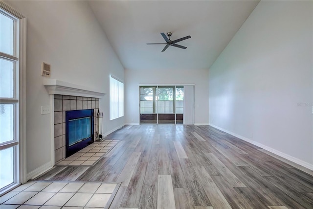 unfurnished living room featuring high vaulted ceiling, light hardwood / wood-style flooring, ceiling fan, and a fireplace