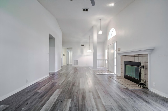 unfurnished living room with a tile fireplace, hardwood / wood-style flooring, and lofted ceiling