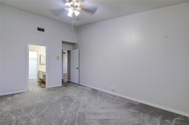 unfurnished bedroom with a high ceiling, ceiling fan, connected bathroom, and light colored carpet