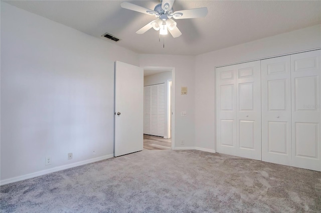 unfurnished bedroom with light colored carpet, a closet, and ceiling fan