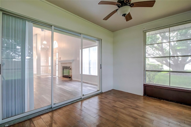 unfurnished sunroom with ceiling fan and a tile fireplace