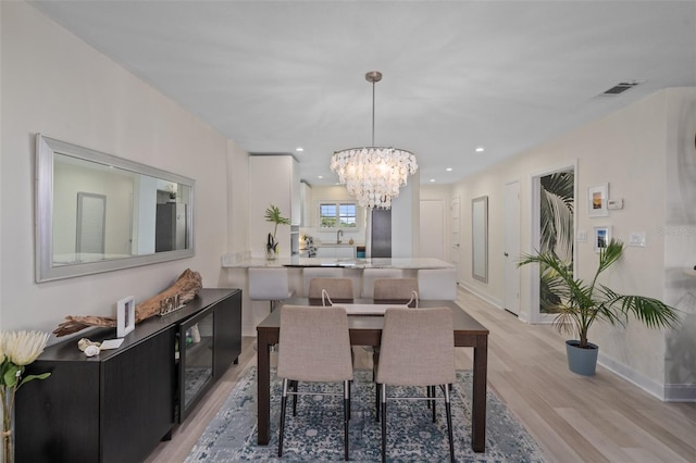 dining space with visible vents, recessed lighting, light wood finished floors, baseboards, and a chandelier