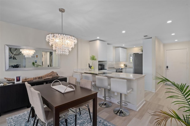 dining room with light wood-style flooring, a notable chandelier, recessed lighting, and visible vents