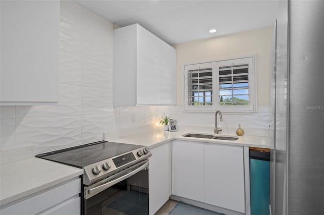 kitchen featuring backsplash, white cabinets, stainless steel range with electric stovetop, and a sink