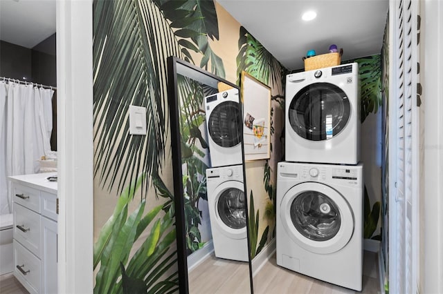 clothes washing area with light wood-type flooring, stacked washer / drying machine, and laundry area