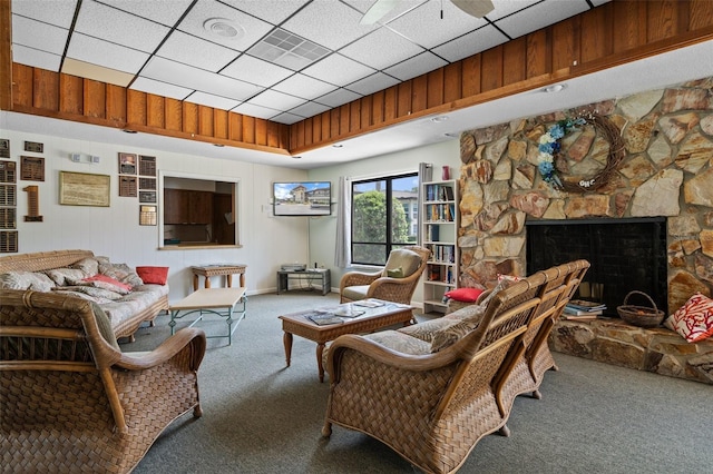 carpeted living area with a stone fireplace and a paneled ceiling