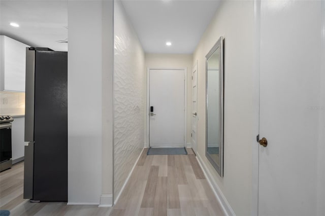 hall with recessed lighting, light wood-type flooring, and baseboards