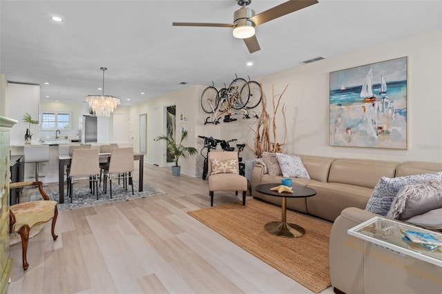 living room featuring ceiling fan with notable chandelier, recessed lighting, light wood-style floors, and visible vents