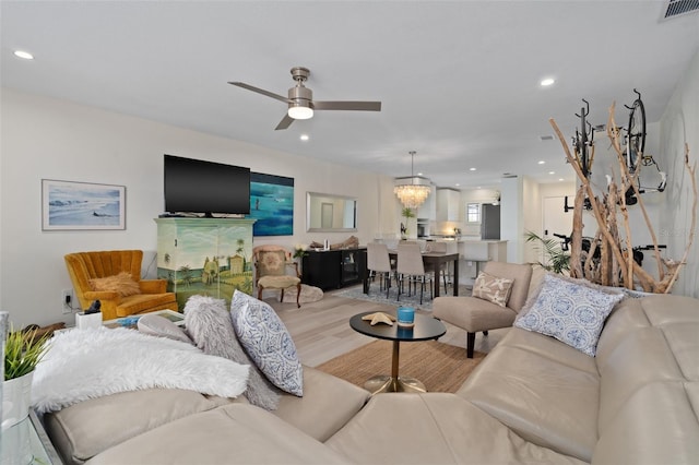 living room with recessed lighting, visible vents, wood finished floors, and ceiling fan with notable chandelier