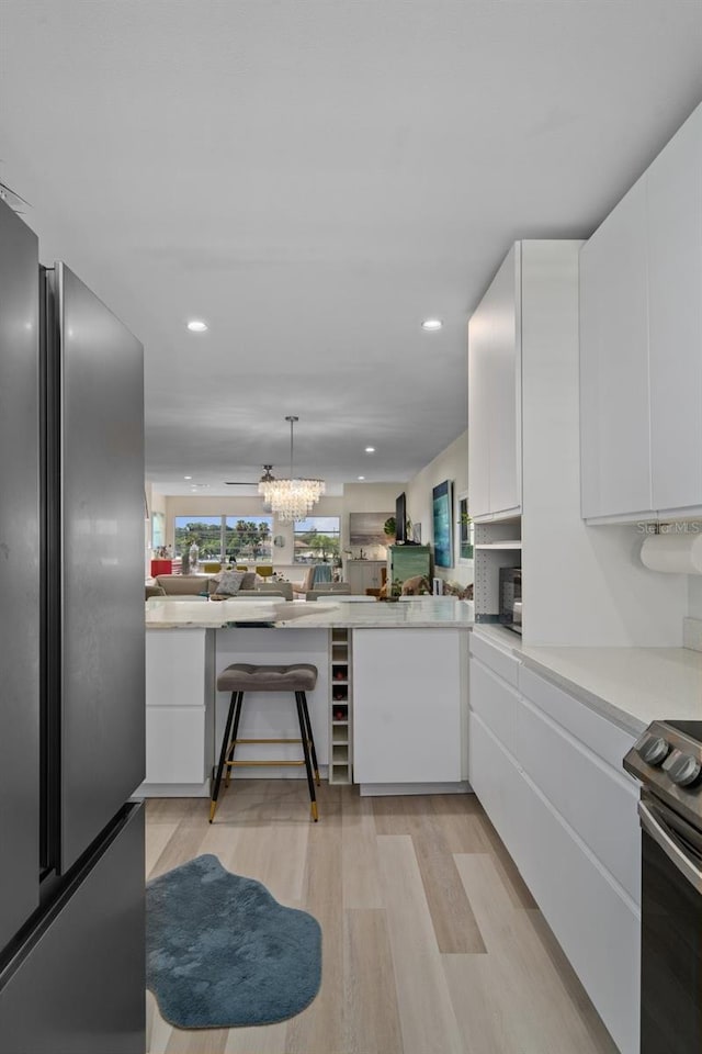 kitchen with light countertops, white cabinets, electric range oven, and freestanding refrigerator