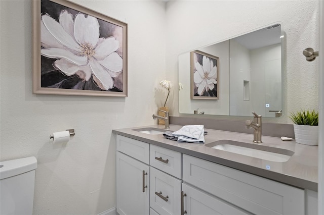 full bathroom with a sink, toilet, walk in shower, and double vanity