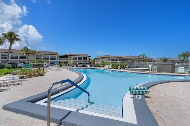 community pool with a patio area and fence