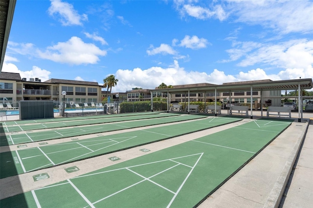 view of community with shuffleboard and fence