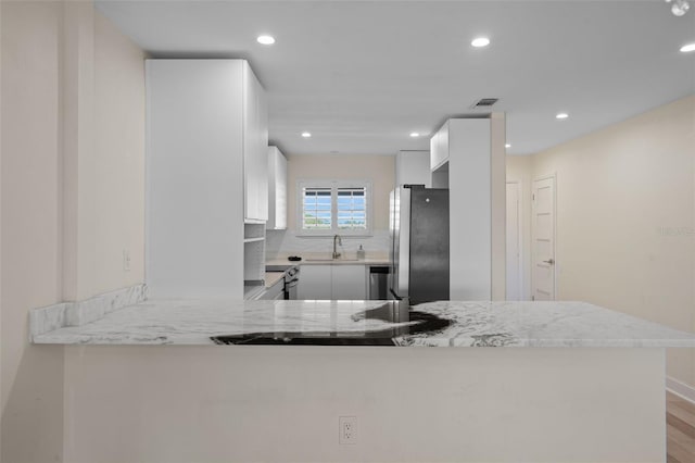 4632 Marine Pkwy Unit 302, New Port Richey, FL 34652 - kitchen with freestanding refrigerator, recessed lighting, white cabinetry, a sink, and a peninsula