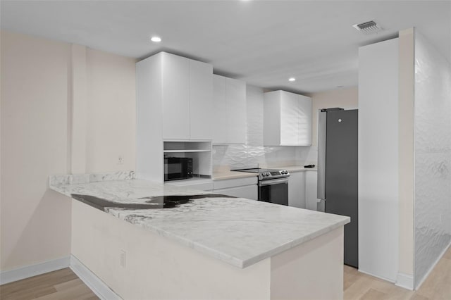 4632 Marine Pkwy Unit 302, New Port Richey, FL 34652 - kitchen featuring stainless steel appliances, a peninsula, white cabinetry, light wood-style flooring, and recessed lighting