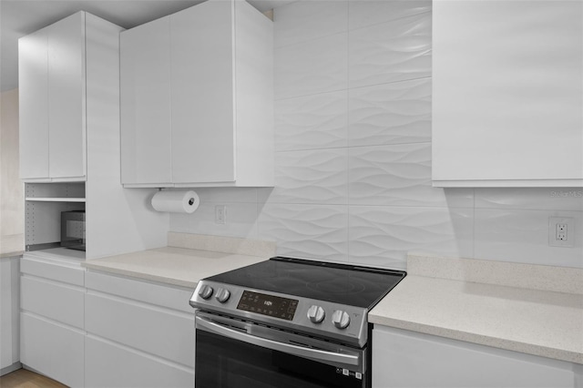 4632 Marine Pkwy Unit 302, New Port Richey, FL 34652 - kitchen featuring stainless steel electric stove, white cabinetry, backsplash, and light countertops