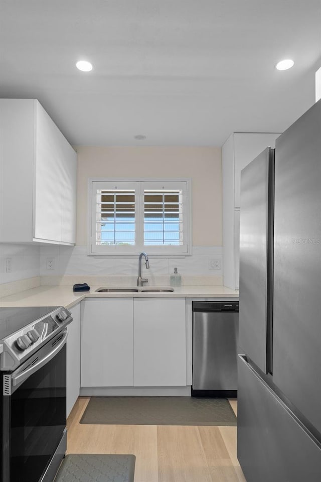 4632 Marine Pkwy Unit 302, New Port Richey, FL 34652 - kitchen with appliances with stainless steel finishes, a sink, white cabinets, light countertops, and light wood-type flooring