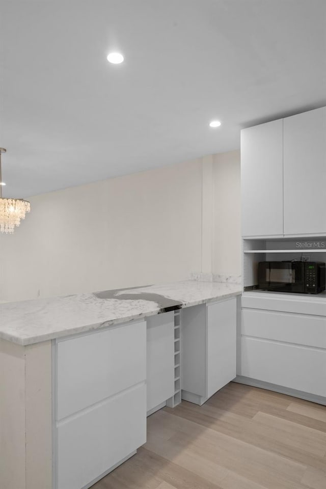 4632 Marine Pkwy Unit 302, New Port Richey, FL 34652 - kitchen featuring white cabinets, black microwave, light wood finished floors, recessed lighting, and a chandelier