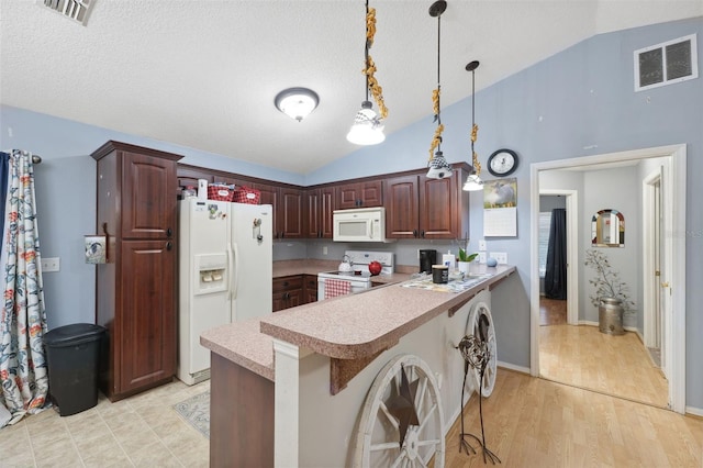 kitchen featuring a kitchen bar, white appliances, decorative light fixtures, light hardwood / wood-style floors, and lofted ceiling