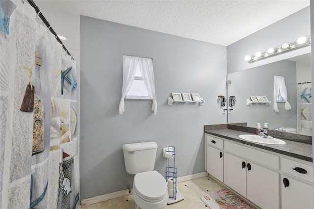 bathroom with vanity, toilet, tile patterned floors, and a textured ceiling