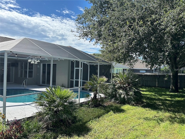 view of pool with a patio, a lawn, and glass enclosure