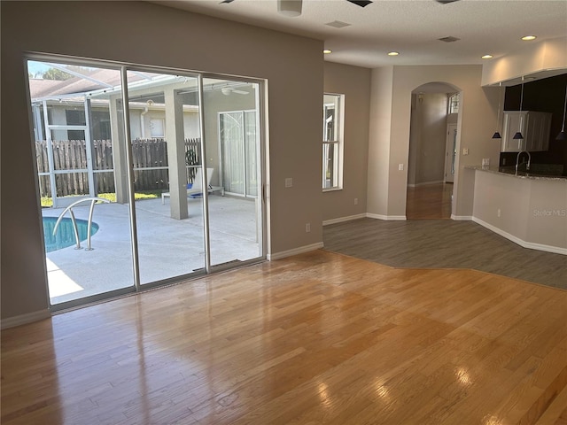 empty room with wood-type flooring, sink, and ceiling fan