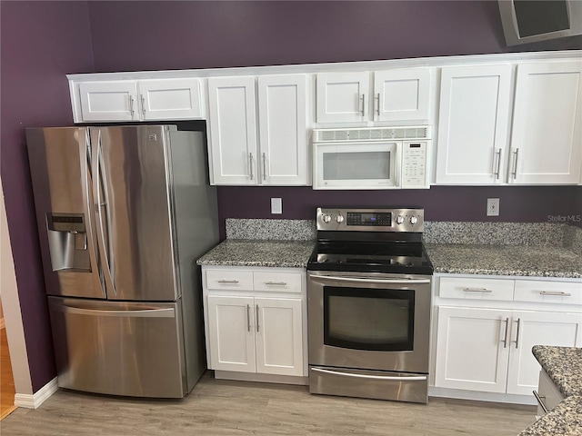 kitchen with appliances with stainless steel finishes, light hardwood / wood-style floors, and white cabinetry