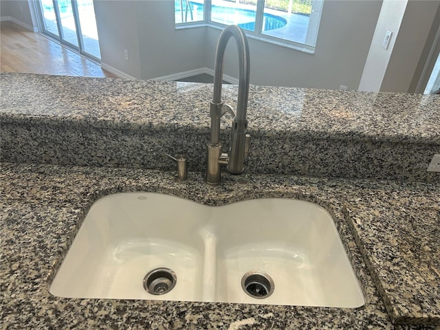 interior details featuring wood-type flooring, dark stone countertops, and sink