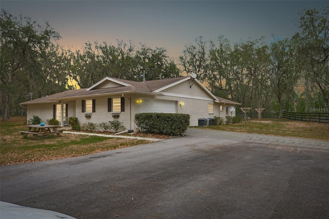 view of front of home featuring a garage, central AC unit, and a lawn