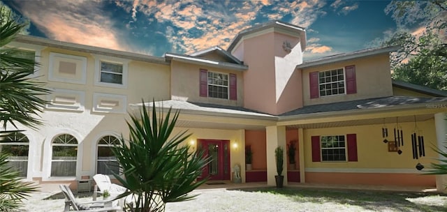 back of property with a porch and stucco siding