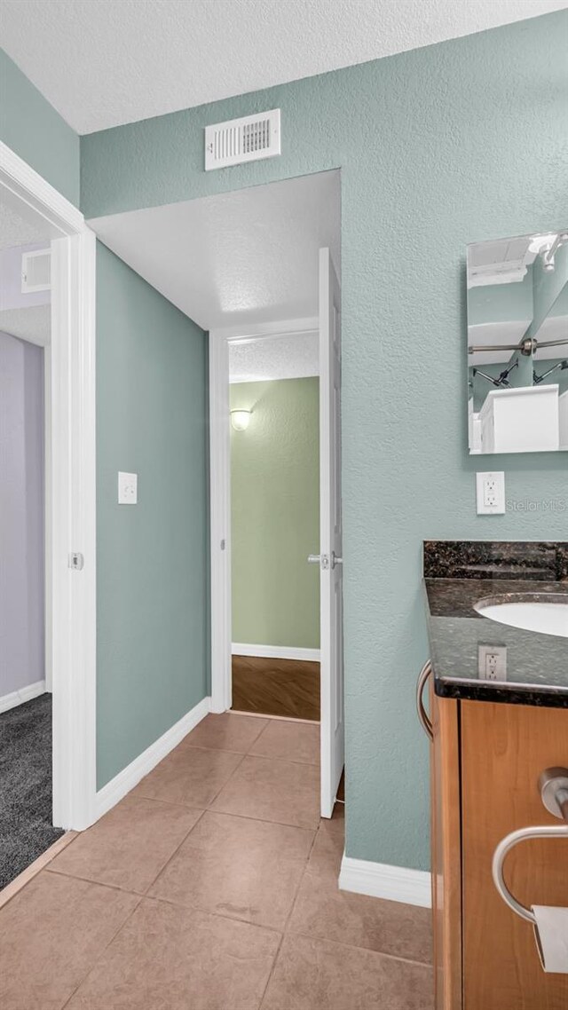 bathroom featuring tile patterned flooring, vanity, and a textured ceiling