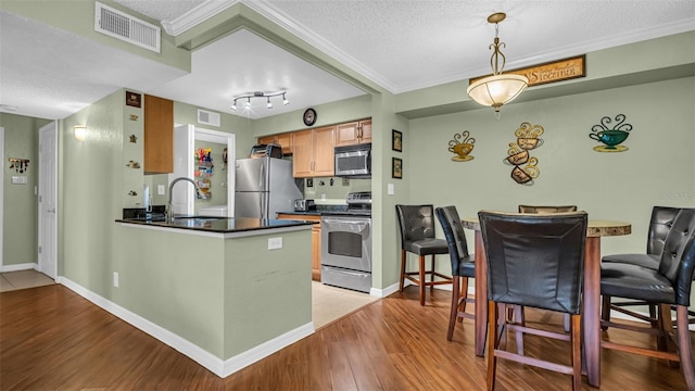 kitchen with stainless steel appliances, rail lighting, sink, and a textured ceiling