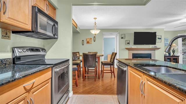 kitchen featuring appliances with stainless steel finishes, dark stone counters, crown molding, and light tile patterned floors