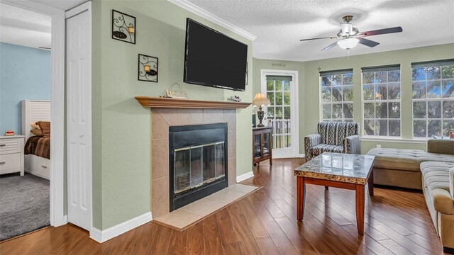 carpeted living room with a textured ceiling, a tile fireplace, and ceiling fan