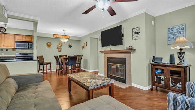 living room featuring hardwood / wood-style flooring, a textured ceiling, a fireplace, and ceiling fan