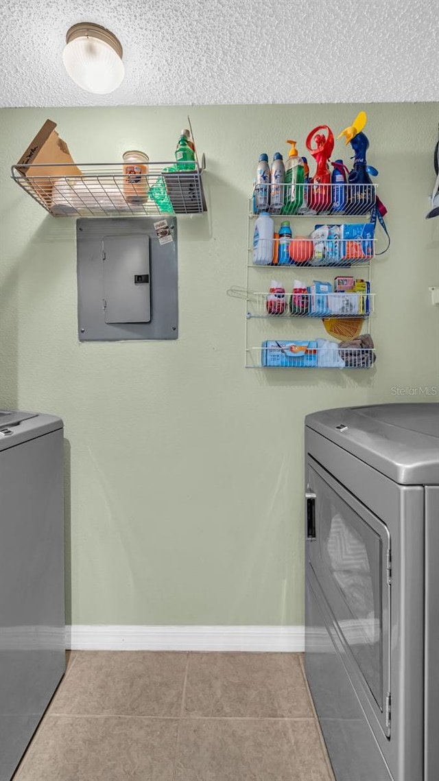 laundry room featuring tile patterned floors, electric panel, and washing machine and clothes dryer