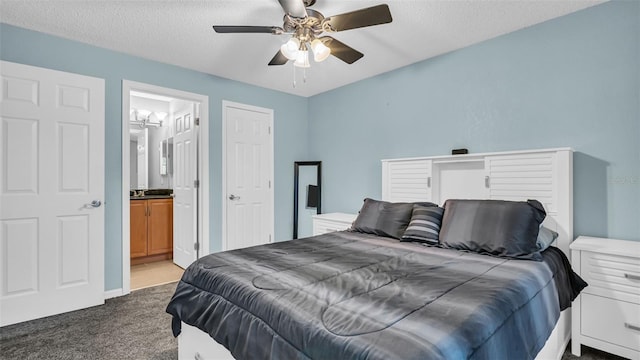 carpeted bedroom featuring a textured ceiling, ensuite bathroom, and ceiling fan