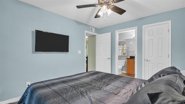 bedroom with a textured ceiling, ensuite bathroom, and ceiling fan