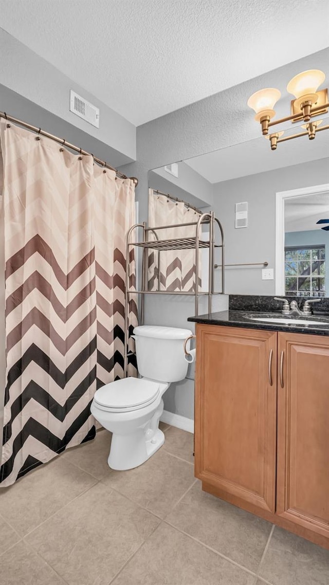 bathroom with vanity, toilet, a textured ceiling, and tile patterned flooring