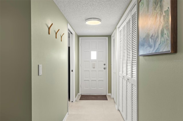 doorway featuring light tile patterned flooring and a textured ceiling