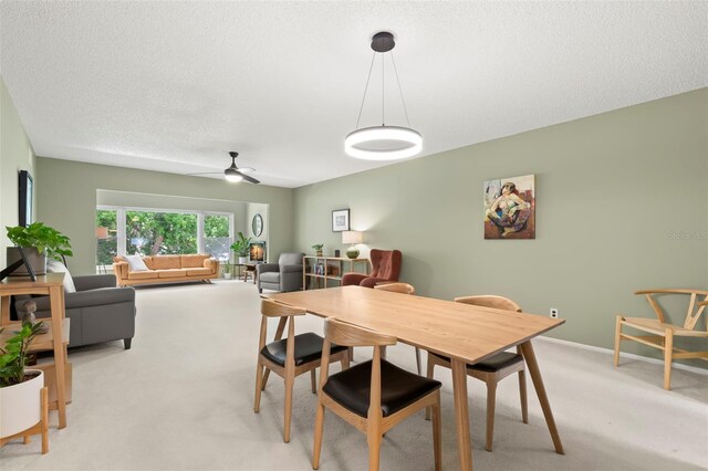 dining room with a textured ceiling, light colored carpet, and ceiling fan