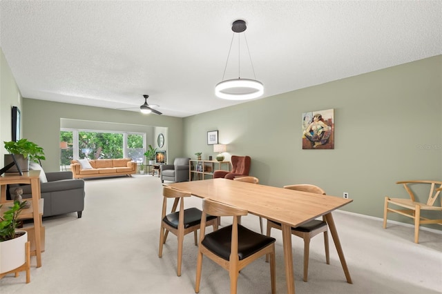 carpeted dining space featuring ceiling fan and a textured ceiling