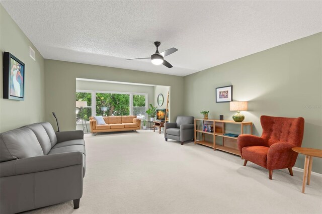 carpeted living room featuring ceiling fan and a textured ceiling