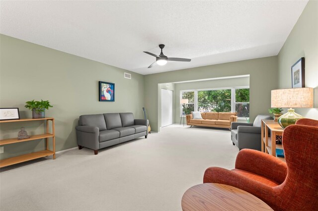 carpeted living room featuring ceiling fan and a textured ceiling