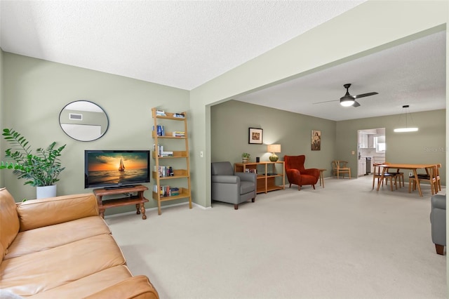 living room featuring ceiling fan, carpet, and a textured ceiling