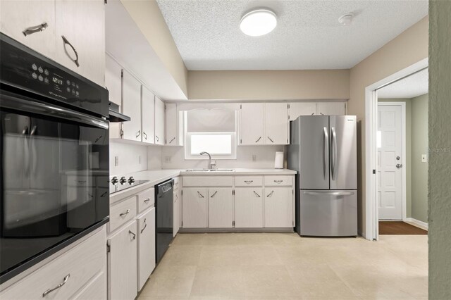 kitchen with sink, a textured ceiling, black appliances, and white cabinets