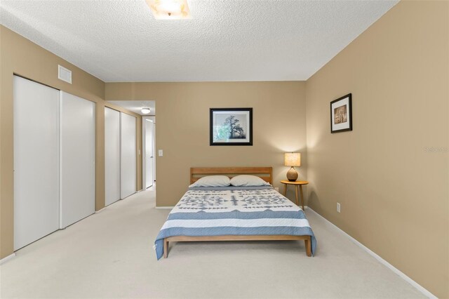 bedroom featuring light carpet and a textured ceiling