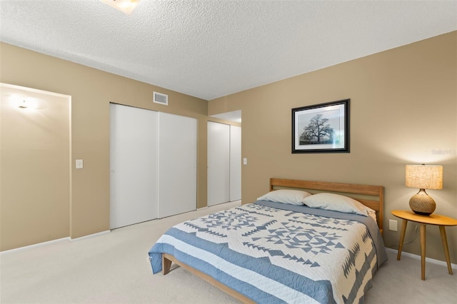 bedroom featuring light colored carpet, a closet, and a textured ceiling